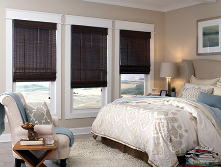 Room scene displaying three walnut natural Roman shades in a bed room