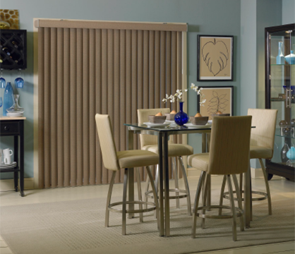 Room scene showing brown fabric vertical blinds over a patio door in a dining room
